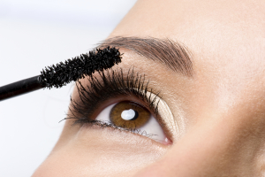 Woman applying mascara on eyelashes